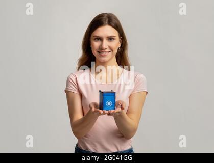 Concetto di separazione dei rifiuti. Smiling Lady Holding Little Recycle Bin per la spazzatura della carta Foto Stock