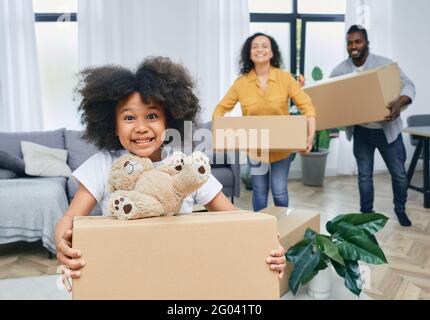 Felice famiglia afroamericana con scatole di cartone e le cose si sposta in una nuova casa. Acquistare o affittare una casa per una famiglia giovane Foto Stock