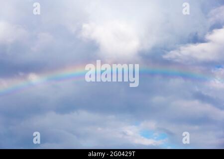 un vero arcobaleno dopo una tempesta e una pioggia calda, contro un cielo blu sullo sfondo Foto Stock