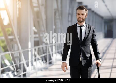 Ricco uomo d'affari con i bagagli a piedi dall'aeroporto Foto Stock