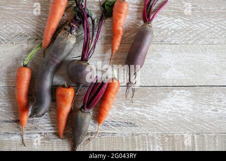 Set di verdure di colore brillante sulla vista dall'alto del tavolo. Carote e barbabietole sono disposte su una superficie di legno, come campioni di superdoods. Copia spazio. Foto Stock