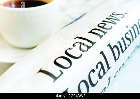 Arrotolato la carta del mattino lungo un lato di una tazza di caffè. Foto Stock