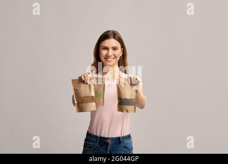 Conservazione di alimenti ecologici. Positivo giovane femmina che tiene tre sacchetti di carta di Kraft DOYPACK Foto Stock