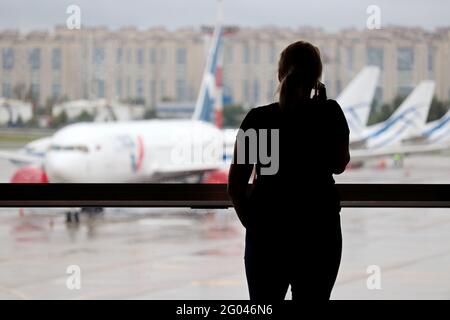 Silhouette di donna che parla sul telefono cellulare nel terminal dell'aeroporto. Passeggero in attesa del volo e guardando gli aerei attraverso la finestra Foto Stock