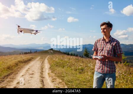 Telecomando drone. Uomo che aziona il controller del copter in montagna. Riprese aeree di Carpathins estivi Foto Stock