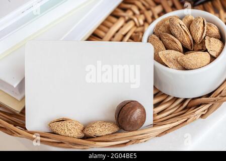 Biglietto da visita con mandorle e noci di macadamia sul vassoio di vimini Foto Stock