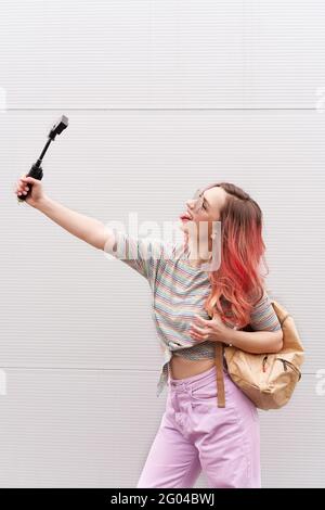 Giovane donna hipster con capelli rosa colorati che fanno vlog da fotocamera d'azione. Foto Stock