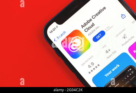 Kharkov, Ucraina - 28 maggio 2021: Applicazione Adobe Creative Cloud App Store sullo schermo di Apple iPhone 12 primo piano con sfondo rosso Foto Stock