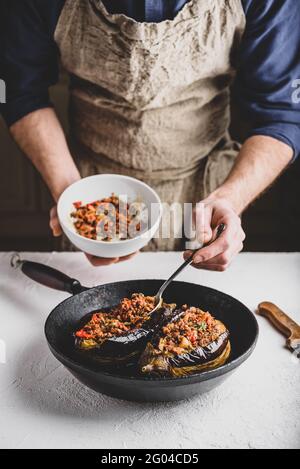 Preparazione delle melanzane farcite con carne macinata, pomodori e spezie. Piatto tradizionale Karniyarik di cucina turca Foto Stock