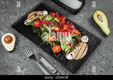 Insalata di salmone gravlax. Insalata di salmone affumicata, con pomodori ciliegini misti avocado olive nere carote germogli cetrioli e lime. Delizioso sano Foto Stock