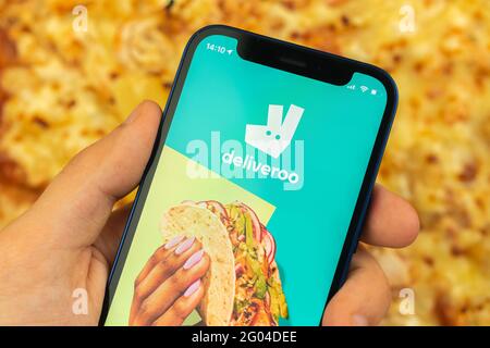 Kharkov, Ucraina - 28 maggio 2021: L'uomo usa l'app per la consegna di cibo Deliveroo Foto Stock