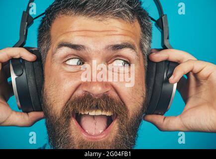 Bell'uomo sorridente con le cuffie. Maschio emozionale con cuffie che ascoltano musica. Foto Stock