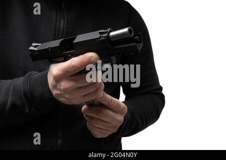 Un uomo in abiti scuri tiene una pistola nelle mani e la ricarica. Arma scaricata in mano. Foto Stock