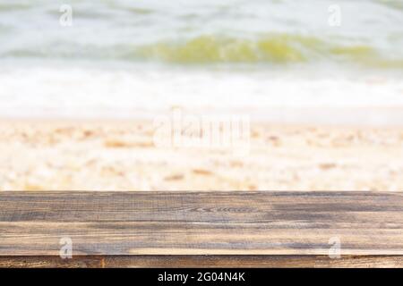 tavolo in legno sulla spiaggia di mare sfocata con conchiglie sfondo Foto Stock