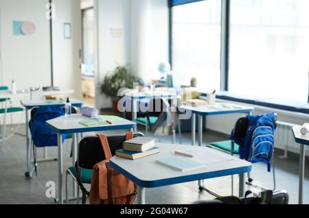 Immagine di sfondo di scrivanie in fila con libri di testo e forniture in aula scuola interni, spazio di copia Foto Stock