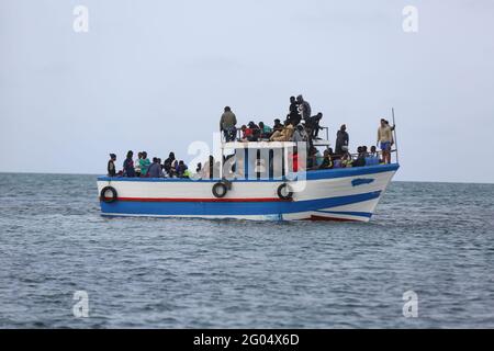 Gli immigrati clandestini attendono la loro evacuazione dalla loro barca rotta il 29 maggio 2021 nel Distretto della Guardia Nazionale Marina del Centro, Sfax, Tunisia. La Tunisia è diventata una posizione centrale per i migranti che cercano di attraversare il Mediterraneo per raggiungere l'Europa. Negli ultimi mesi la guardia costiera tunisina ha fermato centinaia di migranti illegali provenienti da diversi paesi africani. Vogliono lasciare il loro paese a causa della mancanza di opportunità di lavoro, soprattutto dopo la crisi del COVID-19. Il viaggio è molto pericoloso e nelle ultime settimane si sono verificati incidenti di annegamento al largo della costa tunisina, wisconsin Foto Stock