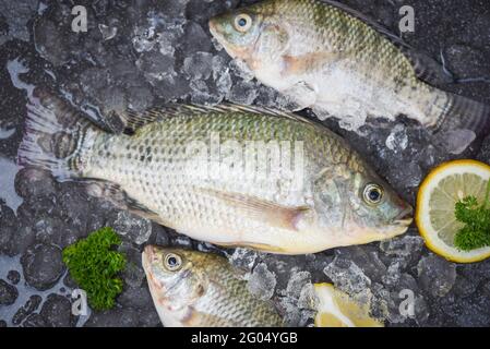 Pesce fresco Tilapia acqua dolce per cucinare cibo con prezzemolo e limone, tilapia cruda dalla fattoria Foto Stock