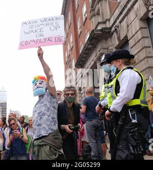 Londra, Regno Unito. 29/05/21. Un protestore si trova di fronte a ufficiali di polizia mascherati e un fotografo che tiene un cartello che denuncia l'uso della maschera. Foto Stock