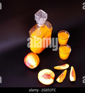 Due ryums, un decanter di liquore fatto in casa di albicocca e pezzi di frutta maturi su sfondo nero. Vista dall'alto. Foto Stock