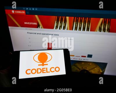 Persona che tiene il cellulare con il logo della società mineraria cilena Codelco sullo schermo di fronte al sito web aziendale. Mettere a fuoco il display del telefono. Foto Stock