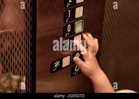 Il bambino è curioso e preme il pulsante dell'ascensore. Il concetto di germi colpito e insicurezza. Foto di alta qualità Foto Stock