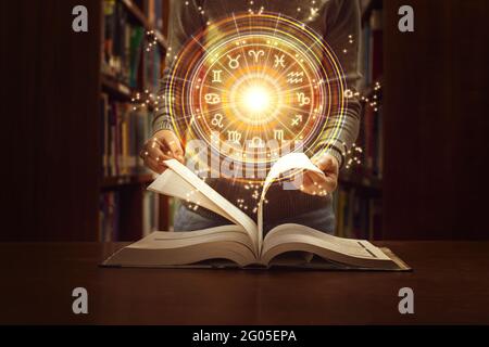 Donna che legge un libro di astrologia. Proiezione astrologica della ruota, scegliere un segno zodiacale. Fidatevi di previsioni future dell'oroscopo, consultando le stelle. Potenza di un Foto Stock