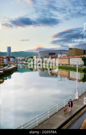 Donna che indossa la maschera facciale cammina con il suo cane lungo la riva del fiume Nervion nel quartiere di Olabeaga, Bilbao, Biscay, Paesi Baschi, Euskadi, Foto Stock