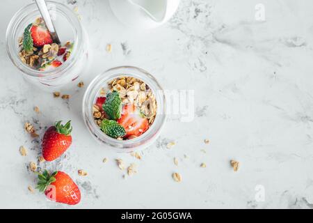 Summet gustosa colazione. Vasetti con parfait in granola, fragole, yogurt su tavola di marmo Foto Stock