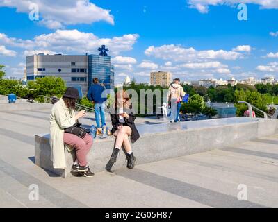 Mosca. Russia. 26 maggio 2021. Un paio di ragazze sono sedute su un parapetto di marmo in una strada cittadina. Le ragazze stanno tenendo gli smartphone. Soleggiata Foto Stock