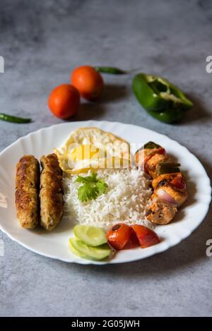 Piatto mediorientale chelo kebab fatto di kebab di agnello alla griglia e servito con pomodori alla griglia e basmati o riso aromatizzato. Foto Stock