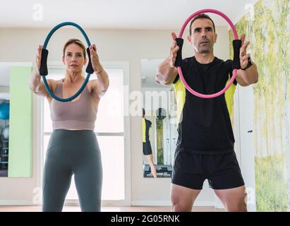 Personal trainer e una donna che fa esercizi di forza con un cerchio elastico in una palestra Foto Stock