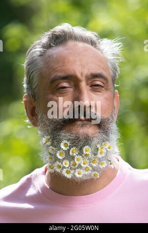 Ritratto creativo dell'uomo anziano con una barba decorata con fiori Foto Stock