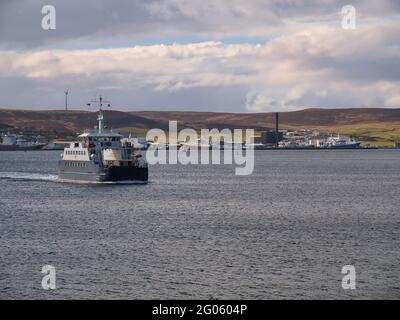 Con il terminal di Holmsgarth e il porto di Lerwick sullo sfondo, il traghetto Fivla si dirige da Lerwick a Bressay in una giornata tranquilla e nuvolosa Foto Stock