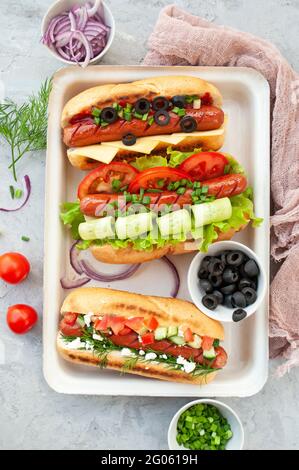 Deliziosi hot dog appena cotti, con farciture assortite su un vassoio Foto Stock