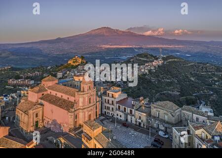 Paesaggio urbano di Centuripe e sullo sfondo il vulcano Etna in eruzione, Sicilia, Italia, Europa Foto Stock
