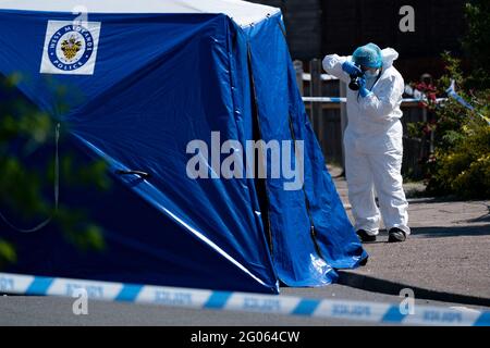 Un ufficiale forense scatta fotografie sulla scena di College Road, Kingstanding, a nord di Birmingham, dove un ragazzo di 14 anni è morto dopo essere stato pugnalato il lunedì sera. La polizia ha avviato un'indagine sugli omicidi e sta cacciando fino a sette persone in relazione all'attacco. Data immagine: Martedì 1 giugno 2021. Foto Stock