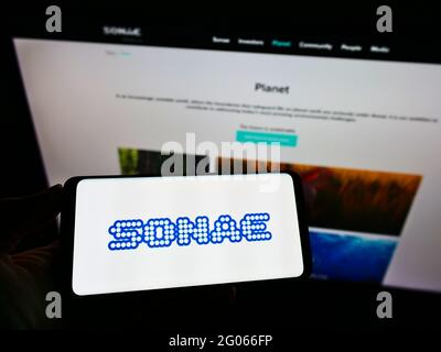 Persona che detiene il cellulare con il logo del conglomerato portoghese Sonae SGPS S.A. sullo schermo davanti alla pagina web dell'azienda. Mettere a fuoco il display del telefono. Foto Stock