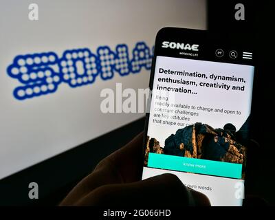 Persona che tiene il cellulare con la pagina web del conglomerato portoghese Sonae SGPS SA sullo schermo davanti al logo dell'azienda. Mettere a fuoco il centro del display del telefono. Foto Stock