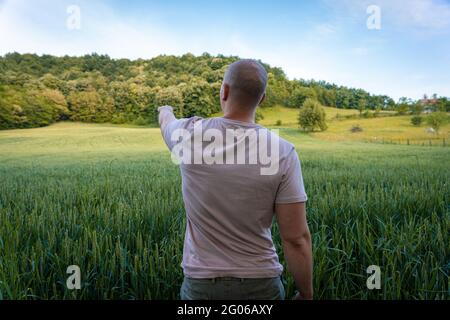 Giovane agricoltore che indica qualcosa in lontananza Foto Stock