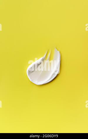 Striscio di crema su sfondo giallo. Consistenza cremosa con ombra chiara. Foto Stock