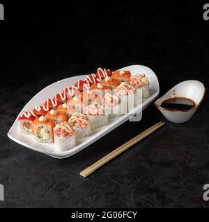 Set di sushi Syake. Rolls Philadelphia, panini al forno con salmone e la California con salmone su sfondo nero testurizzato. Menu sushi. Cibo giapponese. Foto Stock