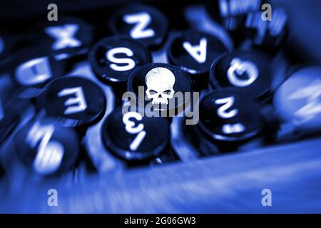 Macchina da scrivere primo piano con sfondo sfocato e cranio bianco a fuoco su uno dei tasti Foto Stock