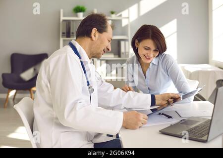 Donna felice che ascolta il medico e che guarda la risonanza magnetica o la scansione a raggi X con un buon risultato Foto Stock