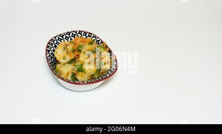 Insalata di patate in una piccola ciotola, antipasto per la colazione, isolato da uno sfondo bianco con spazio per il testo, fuoco selettivo Foto Stock