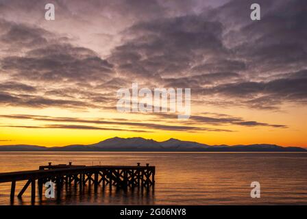 Un bellissimo tramonto dietro l'isola di Arran, preso dal vecchio molo di Portencross nel Nord Ayrshire, Scozia.