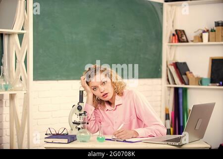 Lavoro stressante dell'insegnante. Pressione nervosa tesa. Educatore stressante. Ragazza stanca espressione stressante con il laptop e il microscopio di lavoro Foto Stock