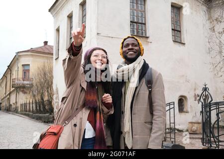 Giovane donna che indica qualcosa mentre si è in piedi con l'uomo in città durante la visita turistica Foto Stock