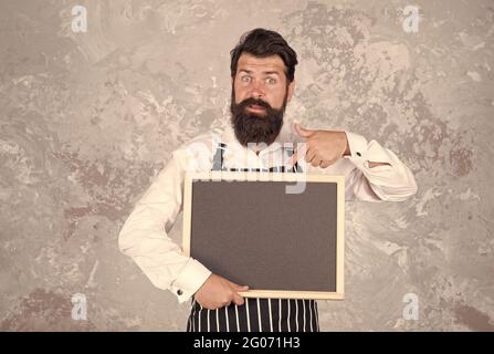 miglior menu dello chef. lavagna con spazio per la copia del testo. panettiere professionale in grembiule. barista sorpreso con barba. pubblicità e cibo. spettacolo di cuoco Foto Stock