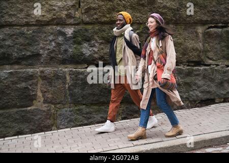 Giovane coppia di turisti che tengono le mani e camminano lungo la vecchia strada Foto Stock