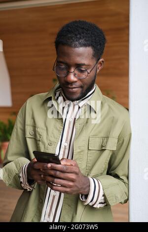 Giovane africano che lavora online sul cellulare Foto Stock